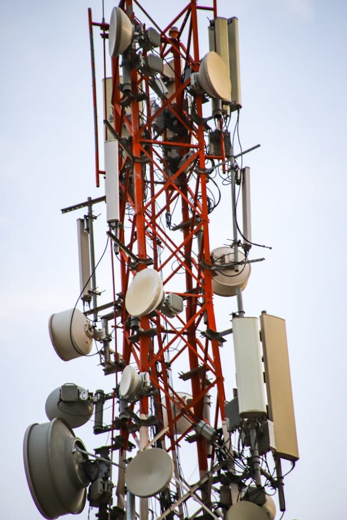 A close-up of a tall telecommunication tower with antennas and equipment against the sky.